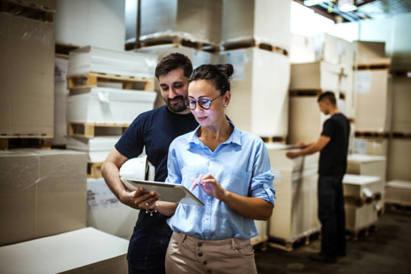 Small Business Leader using a tablet to show data to an employee in a warehouse